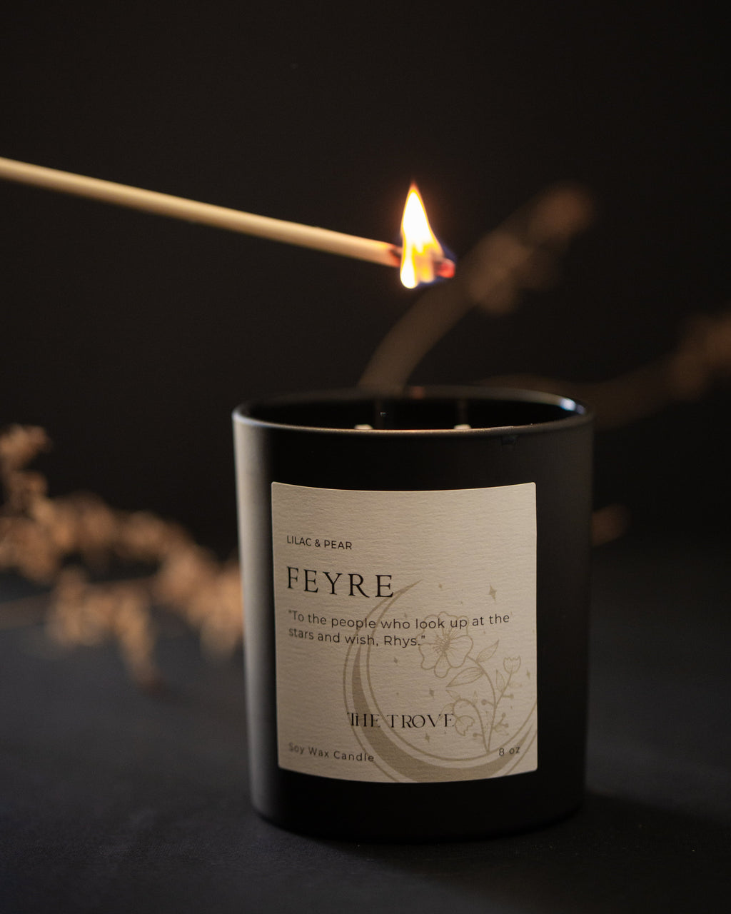 Candle labeled 'Feyre' being lit with a match against a dark background