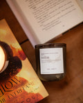 Candle labeled 'DIEM' next to an open book on a wooden surface