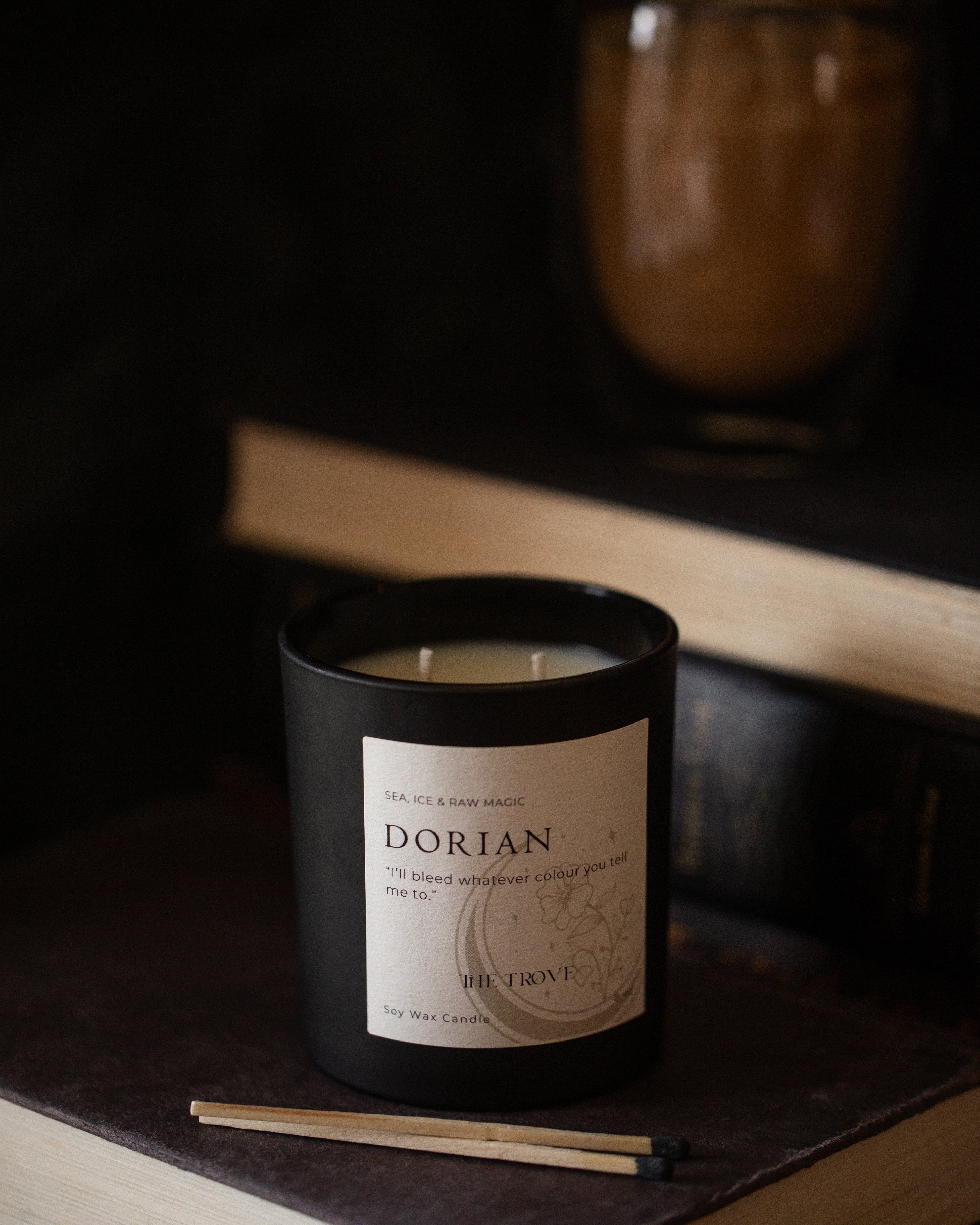 Candle labeled 'Dorian' on a dark surface with a blurred background