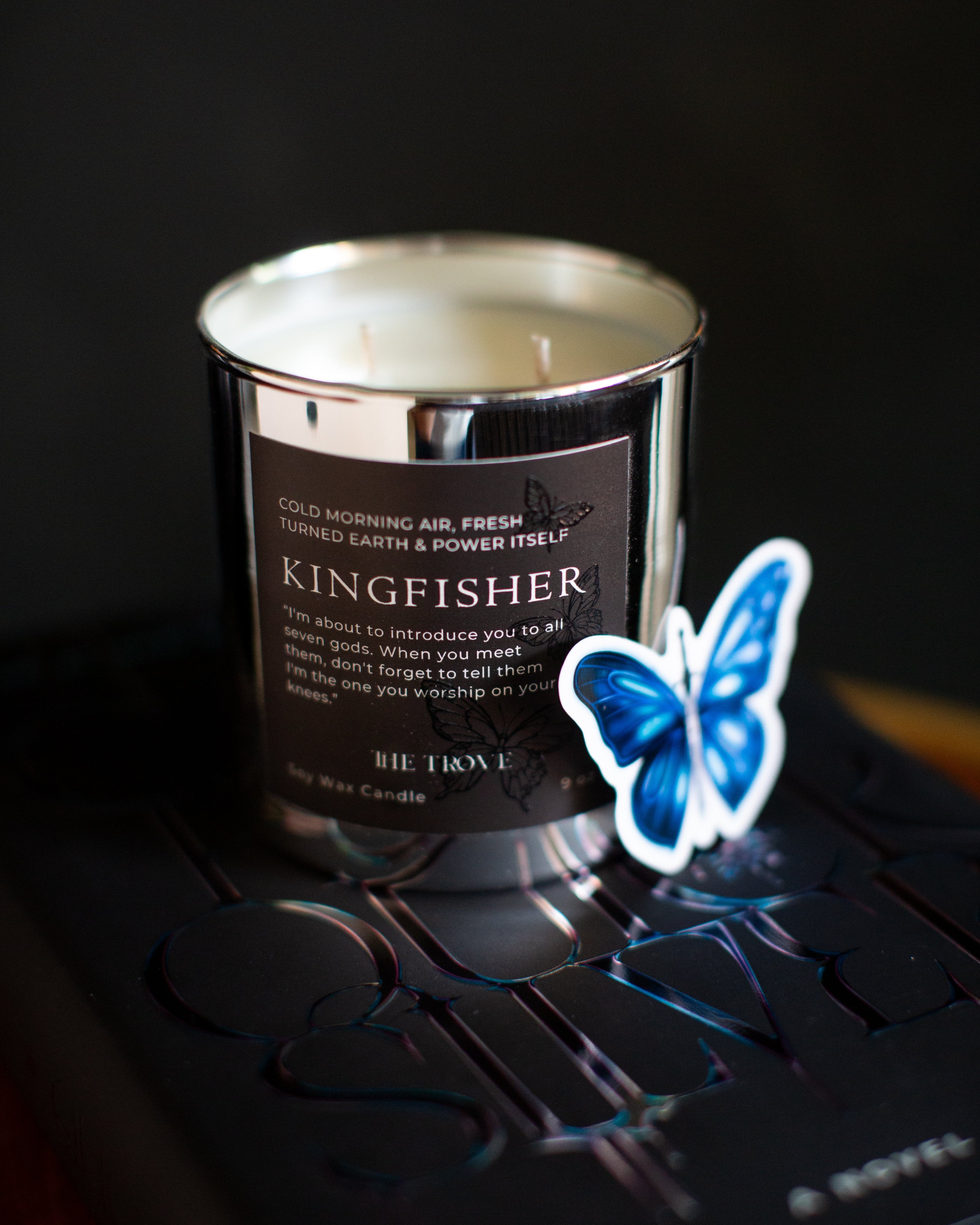 Candle labeled 'Kingfisher' with a blue butterfly on a dark background