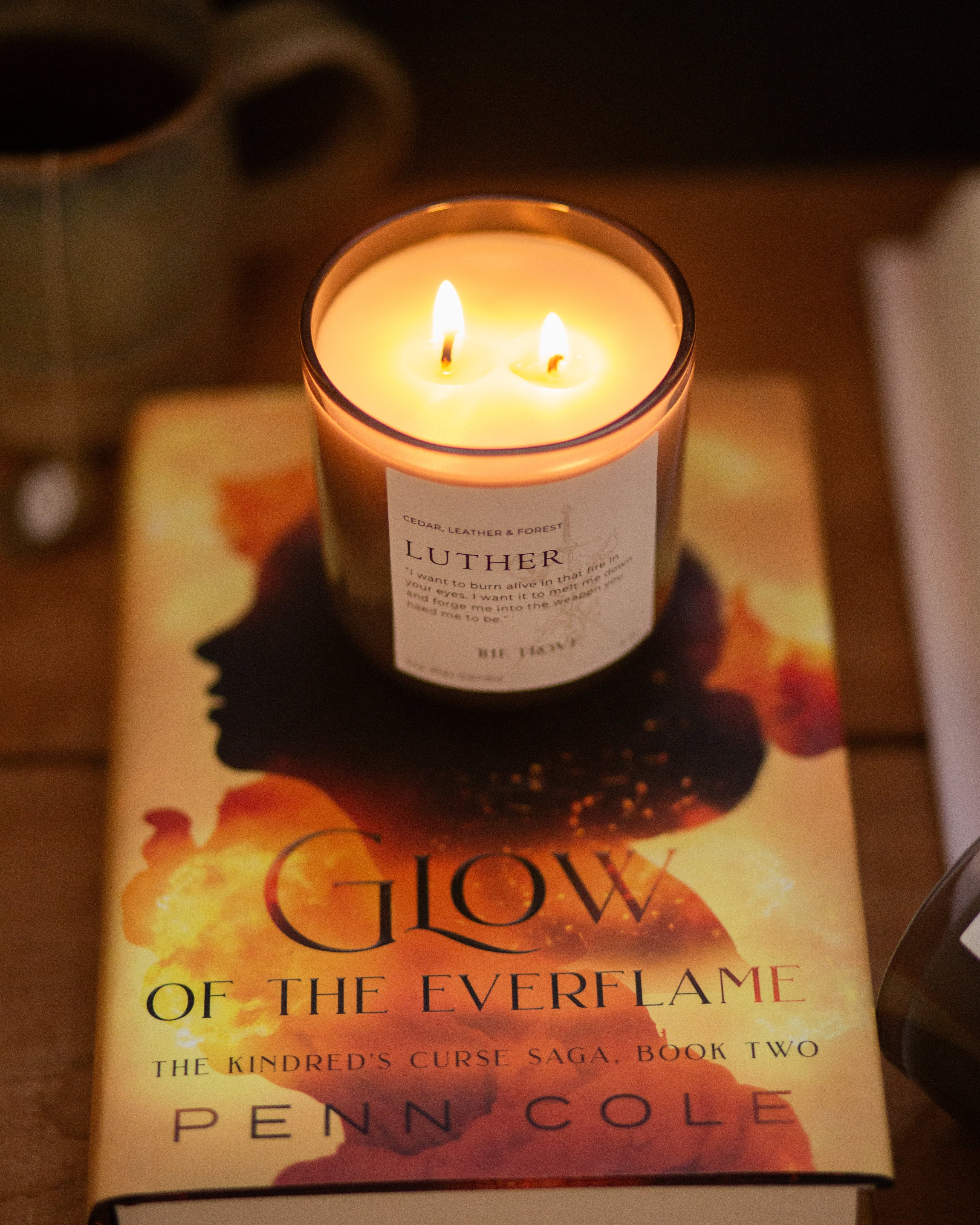 Candle on a book titled 'Glow of the Everflame' by Penn Cole with a blurred background