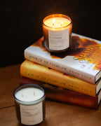 Candle labeled 'Luther' on a stack of books with another candle in the foreground.