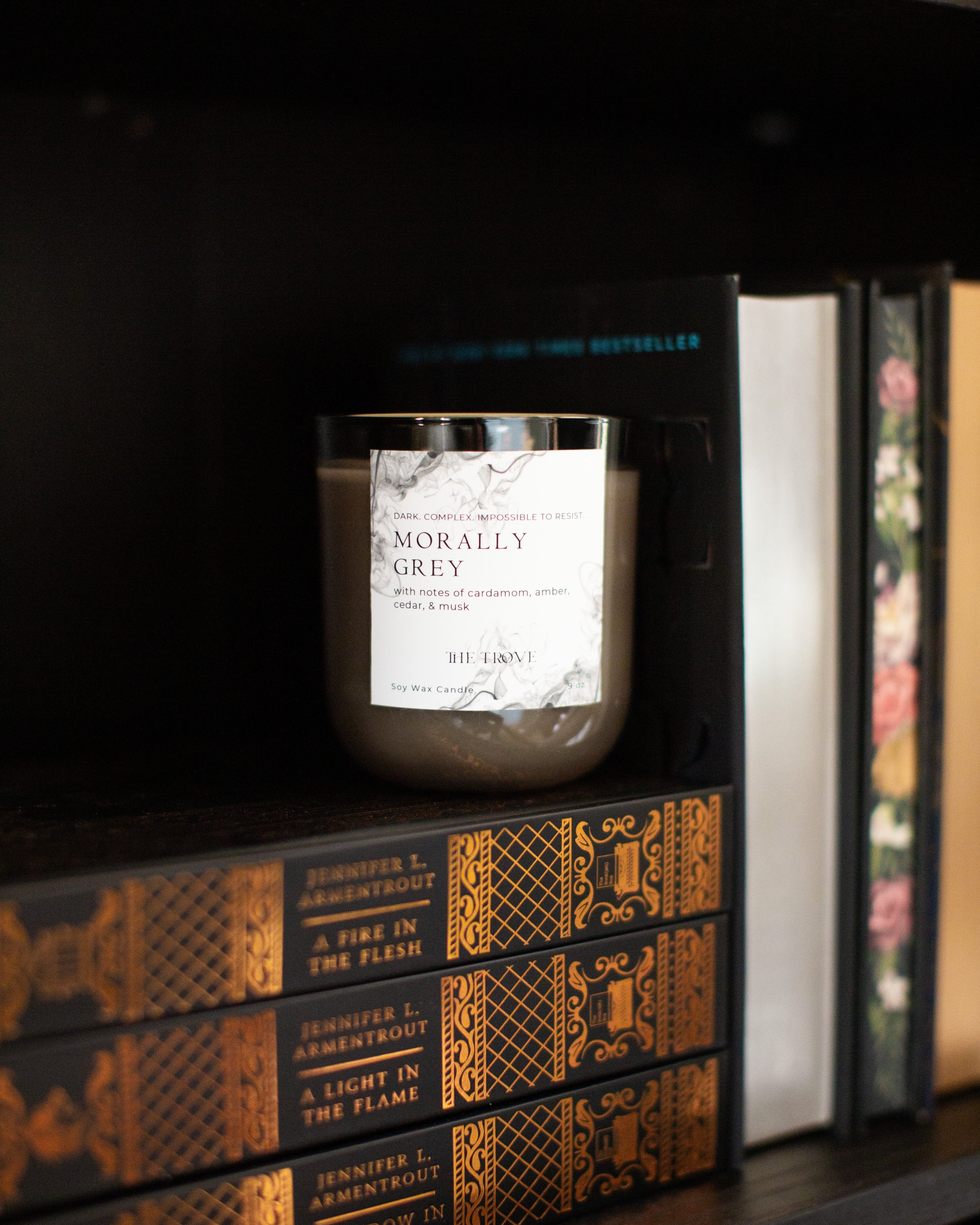 Candle labeled 'Morally Grey' on a shelf with books