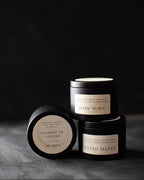 Three black candles with labels on a dark background