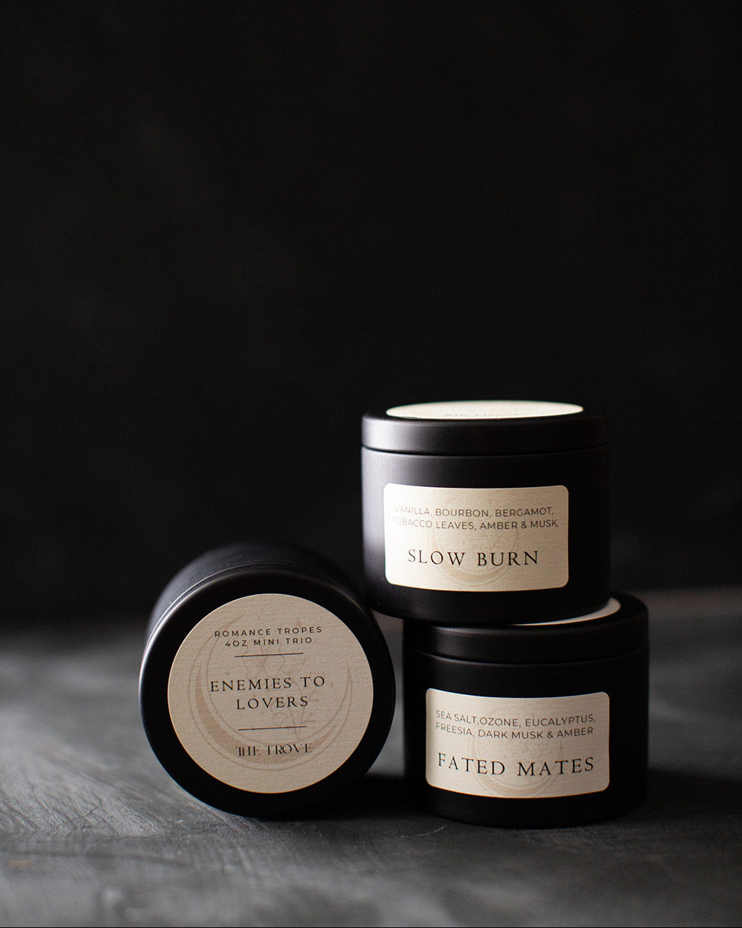 Three black candles with labels on a dark background