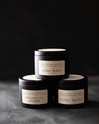 Three black candles stacked on a dark surface with visible labels.