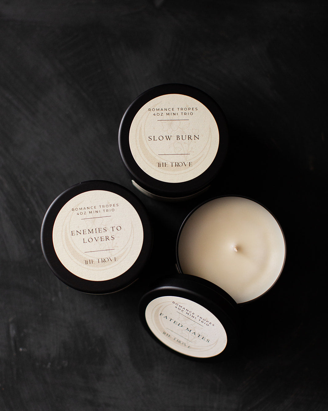 Three candles with labels on a dark surface