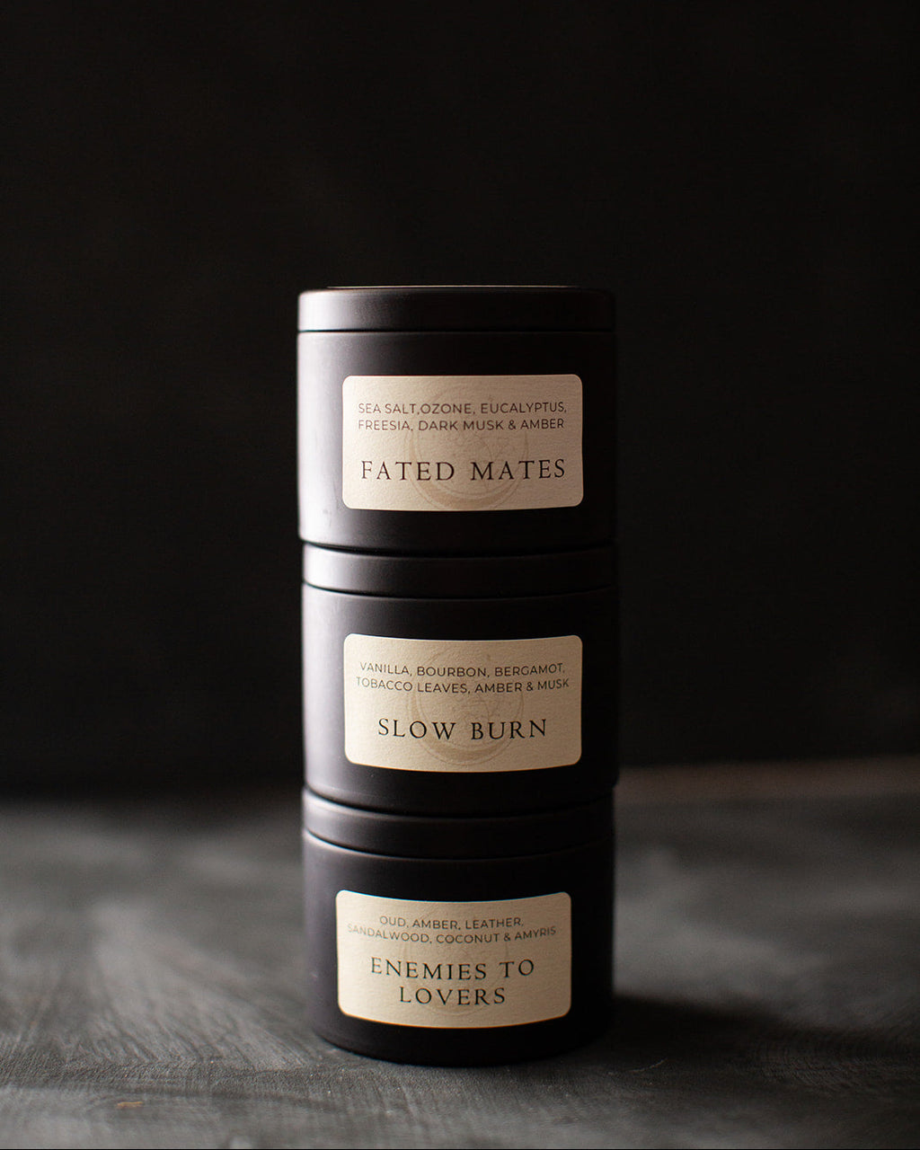 Three black cylindrical candles with labels on a dark background