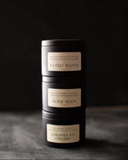 Three black cylindrical candles with labels on a dark background