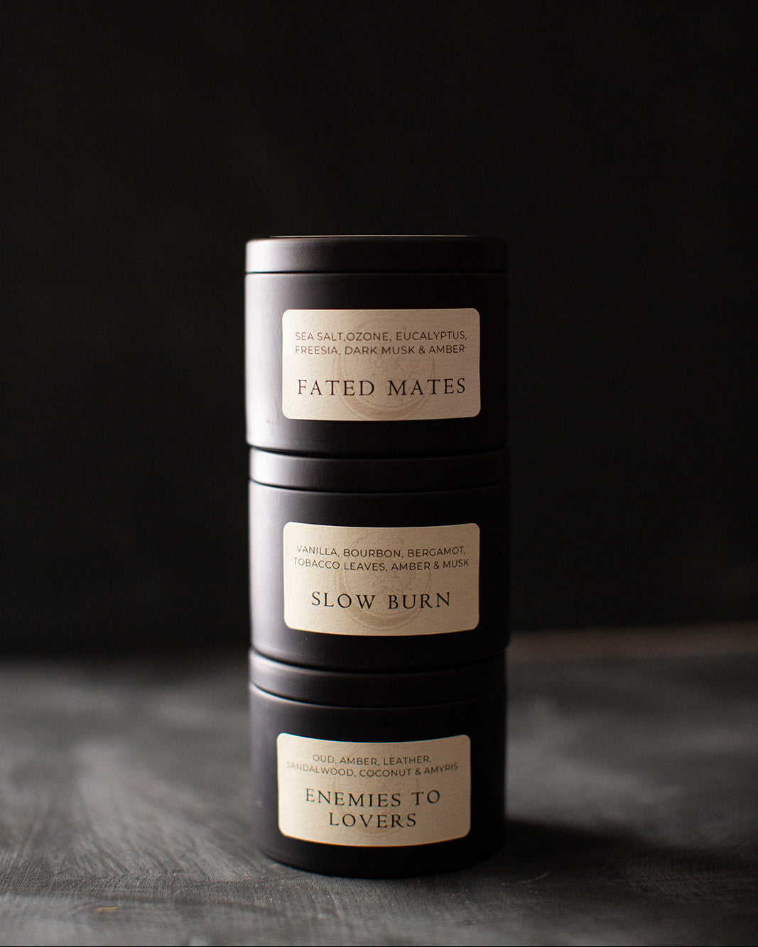 Three black cylindrical candles with labels on a dark background