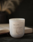 Candle labeled 'TBR List' by The Trove on a dark background with an open book.