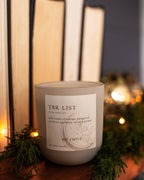 Candle labeled 'TBR List' with books and decorative lights in the background