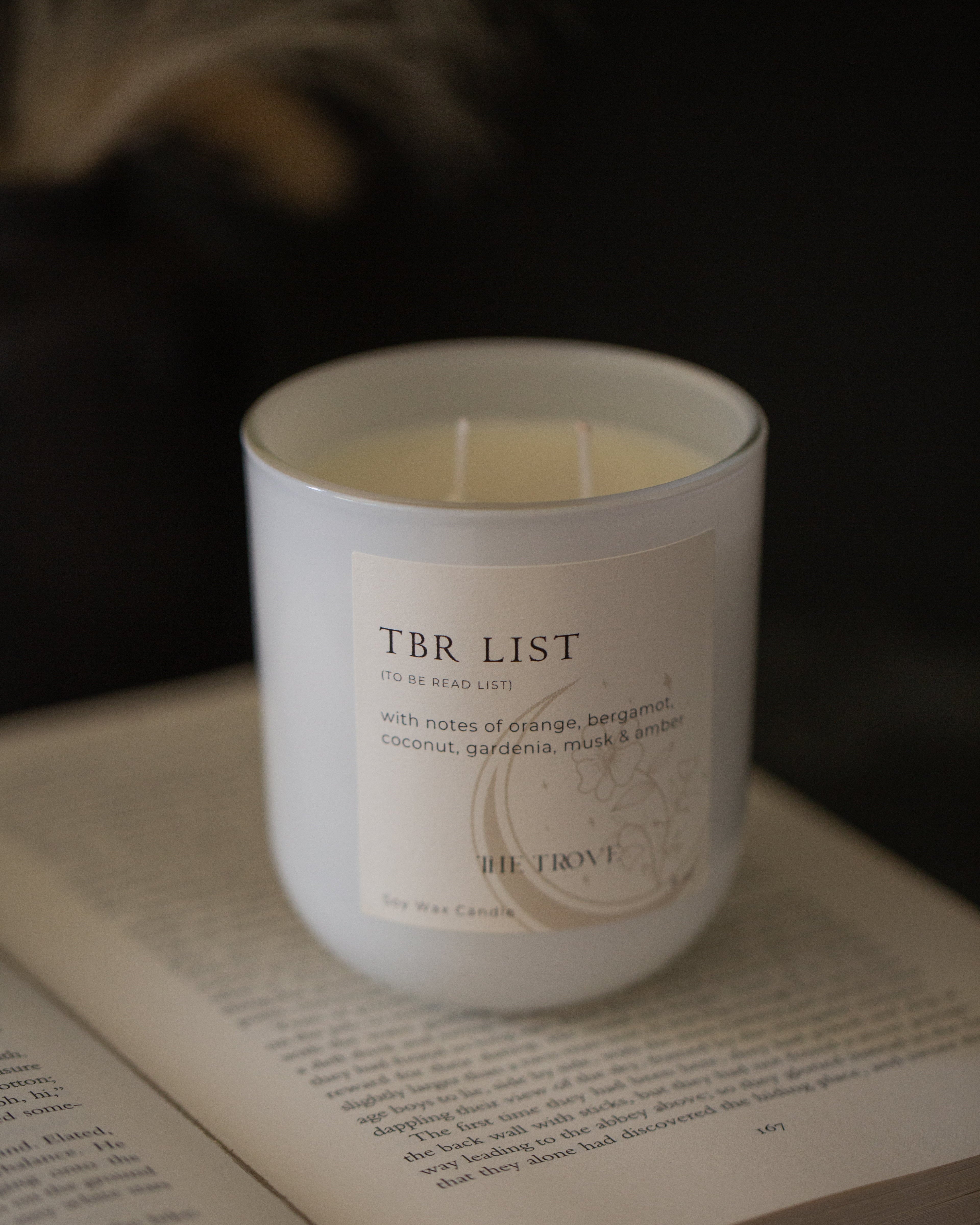 Candle labeled 'TBR List' on an open book with a dark background