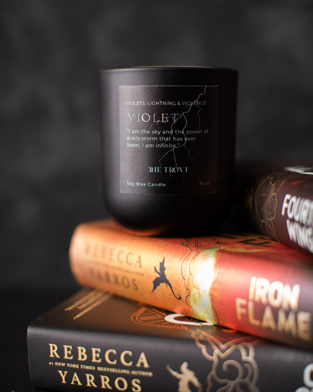 Black candle labeled 'Violet's' on top of books with a dark background