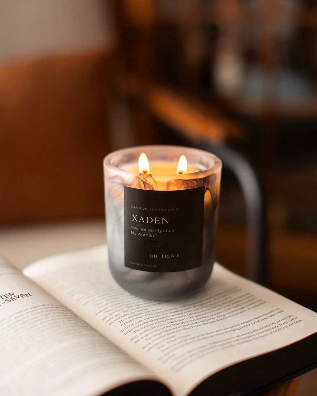 Candle labeled 'Xaden' on an open book with a blurred background