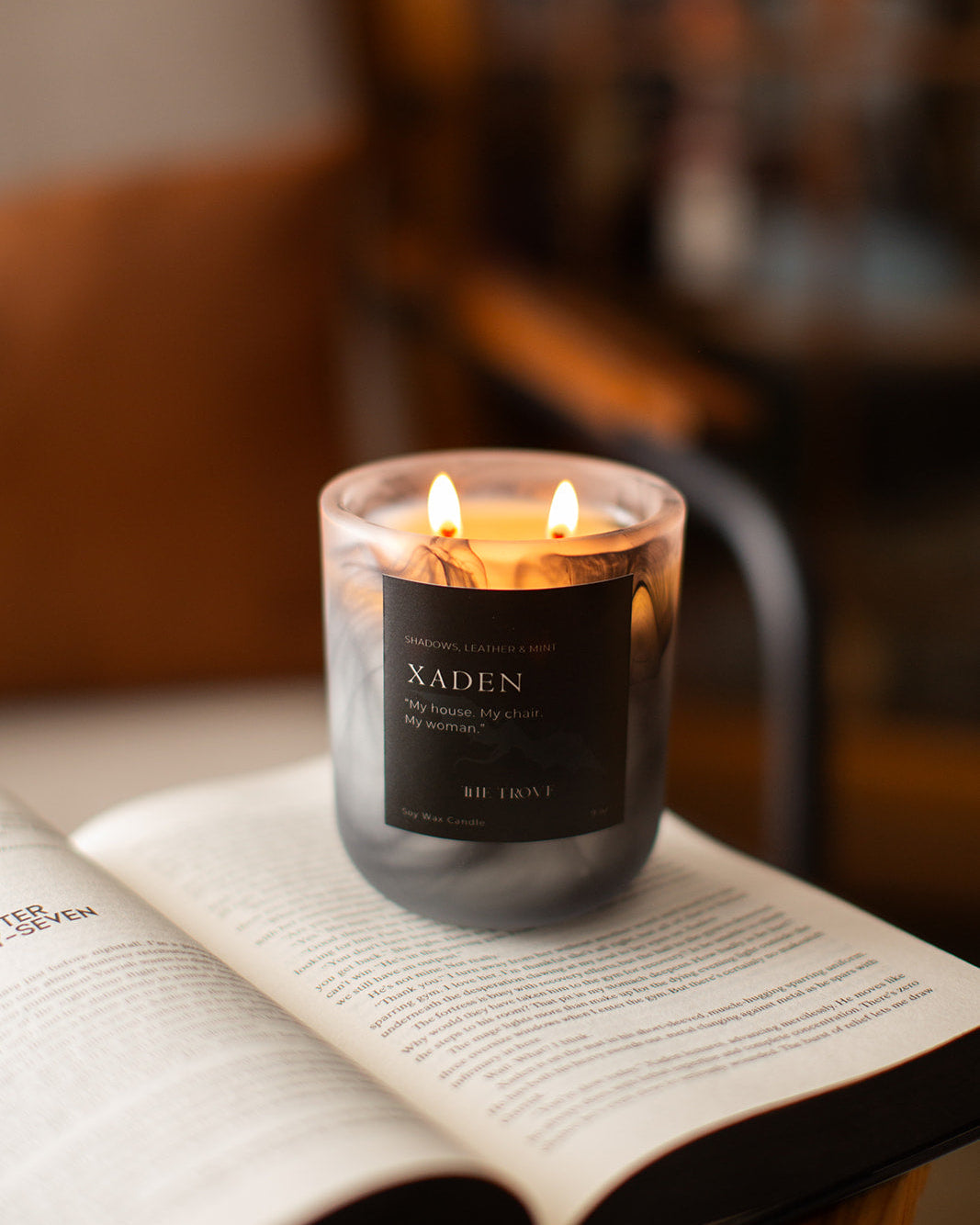 Candle labeled 'Xaden' on an open book with a blurred background