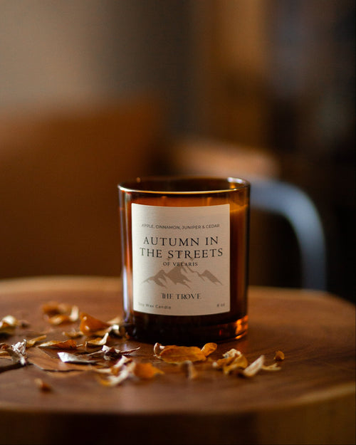 Candle labeled 'Autumn in the Streets' on a wooden surface with blurred background