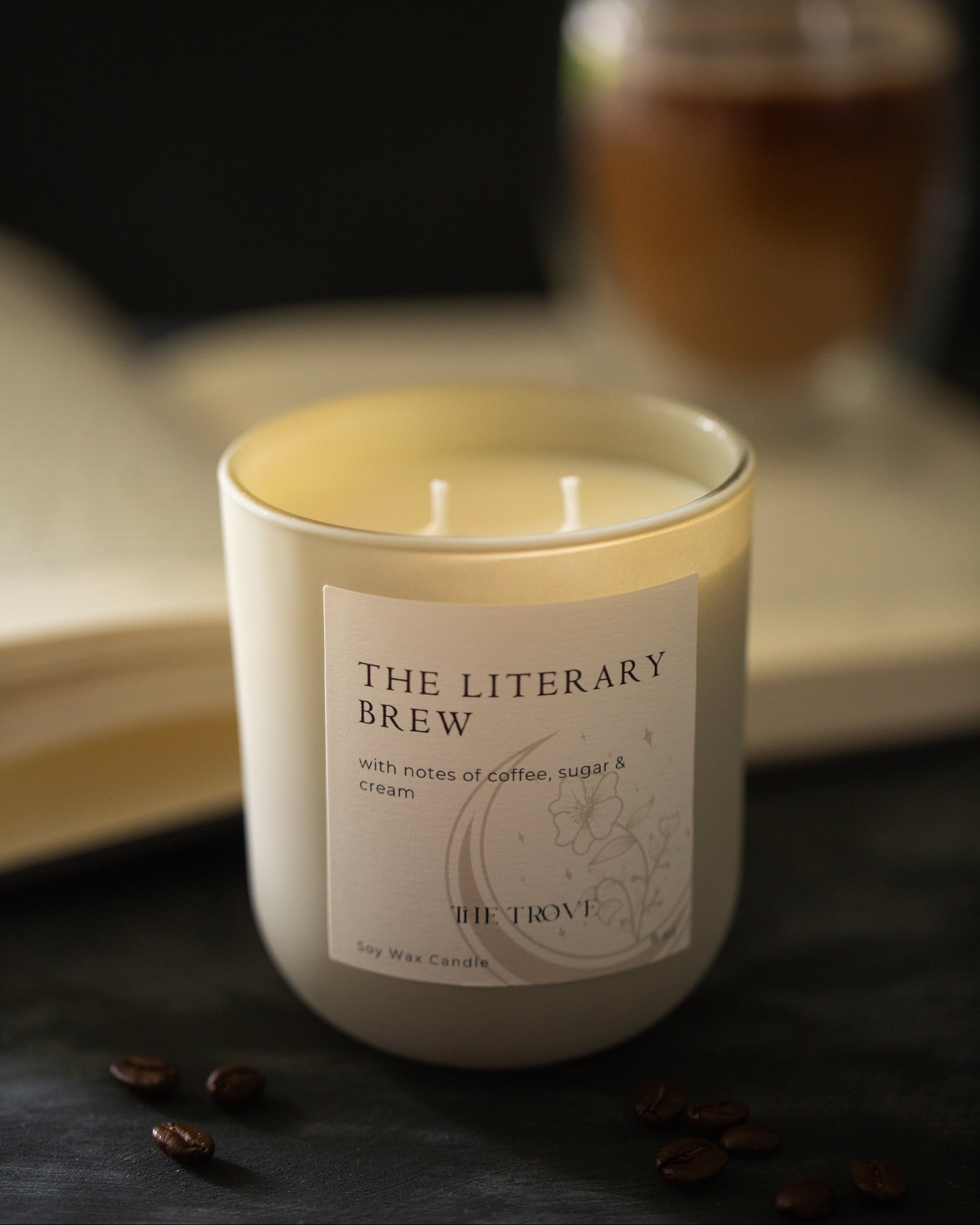 Candle labeled 'The Literary Brew' with a blurred background of a book and glass.