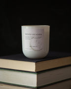 Candle labeled 'Mood Reader' on a stack of books with a dark background