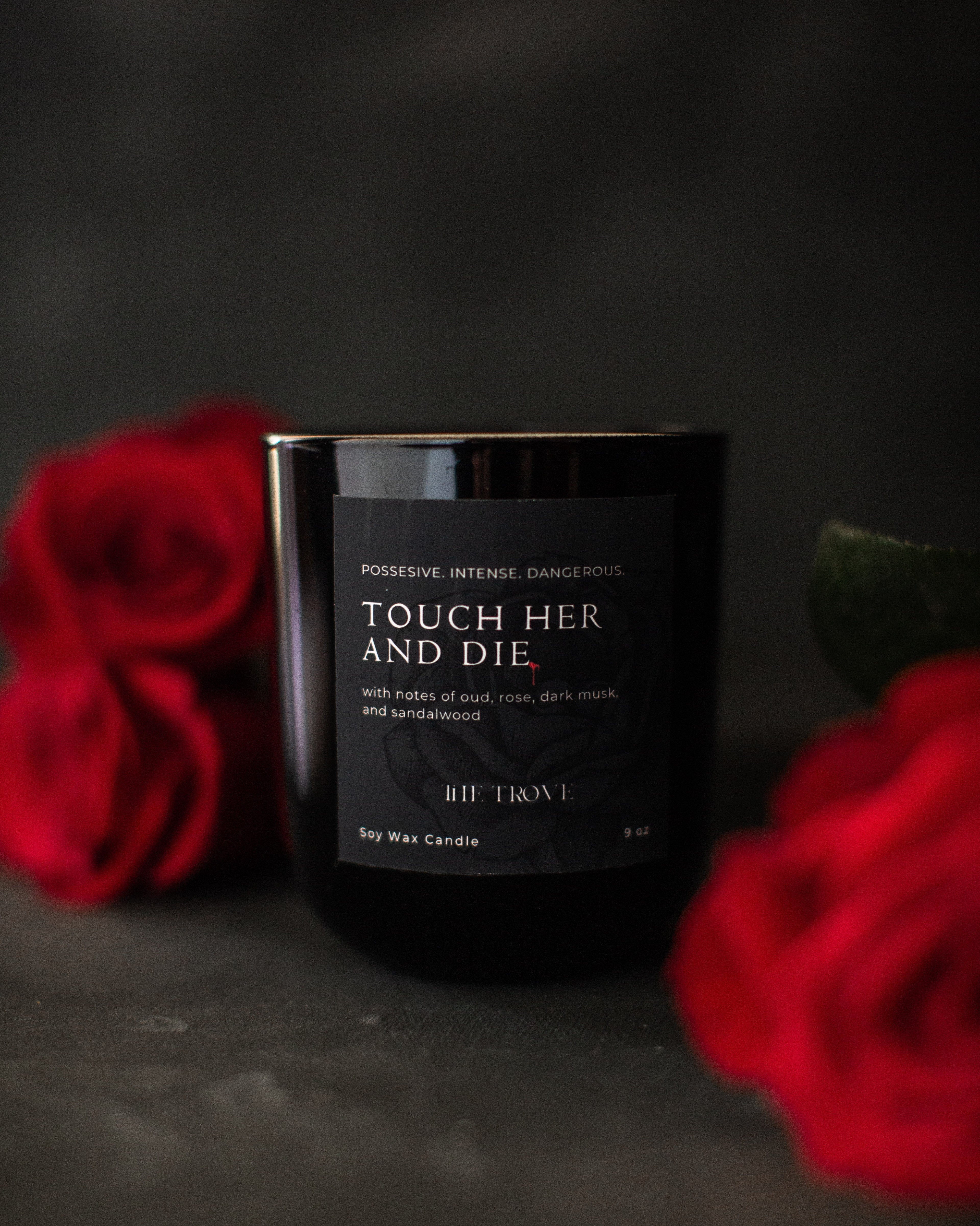 Black candle labeled 'Touch Her and Die' with red roses on a dark background
