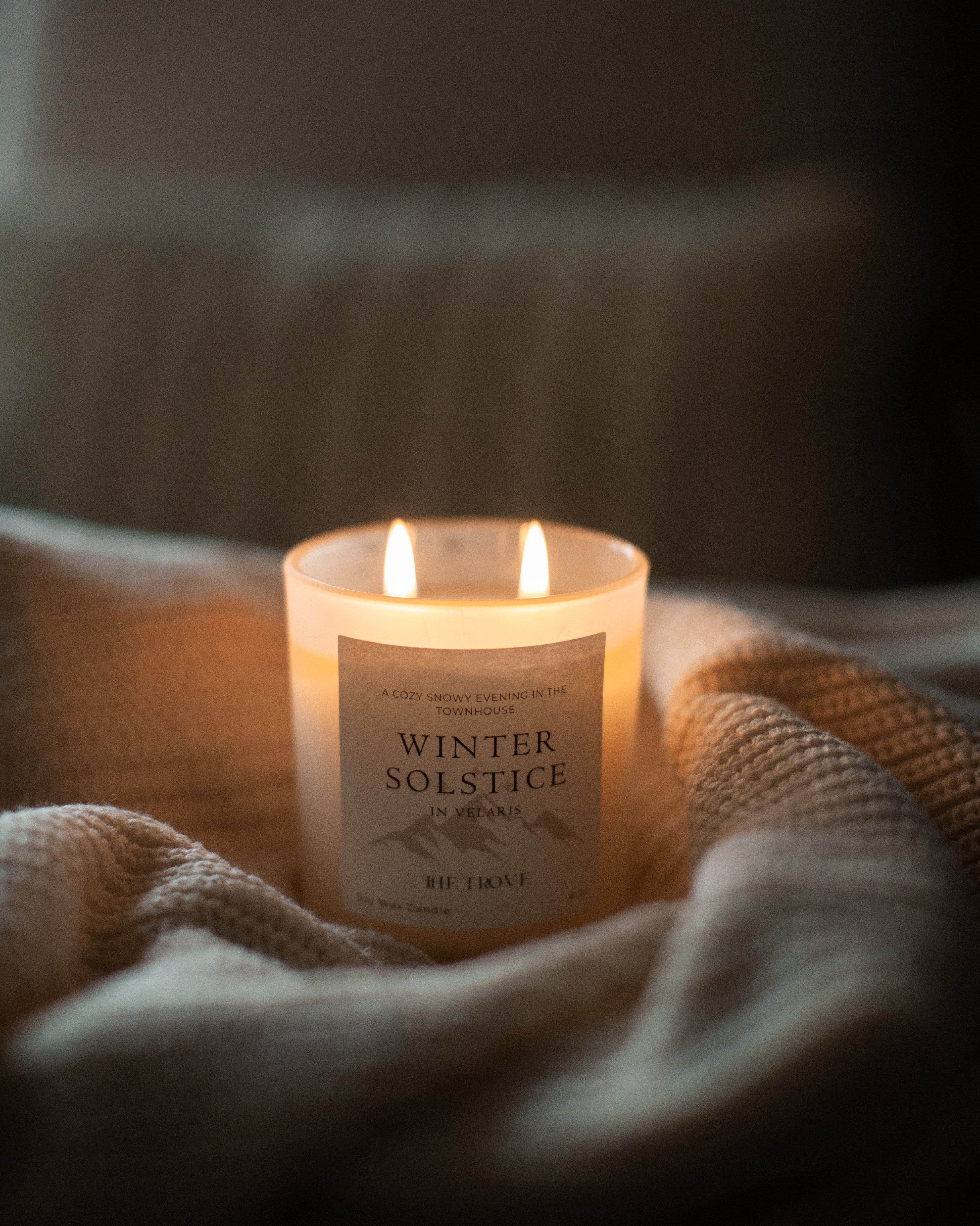 Candle labeled 'Winter Solstice' on a textured surface with a blurred background